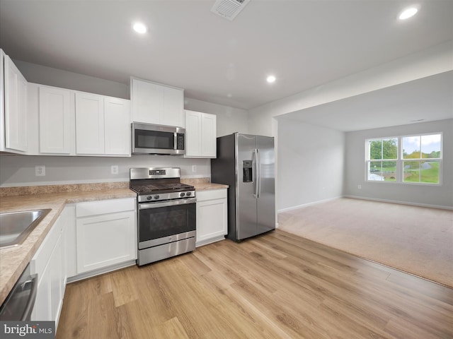 kitchen featuring light carpet, appliances with stainless steel finishes, sink, and white cabinetry