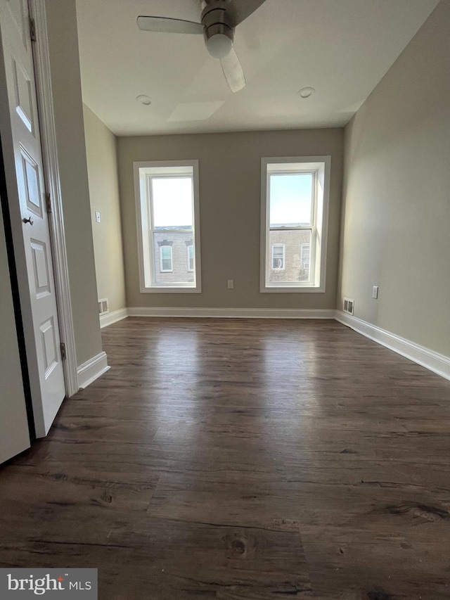 empty room featuring plenty of natural light, dark hardwood / wood-style floors, and ceiling fan