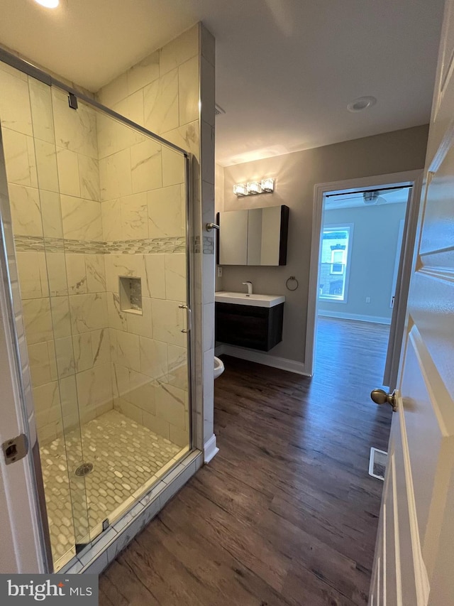 bathroom featuring hardwood / wood-style flooring, vanity, toilet, and a shower with door