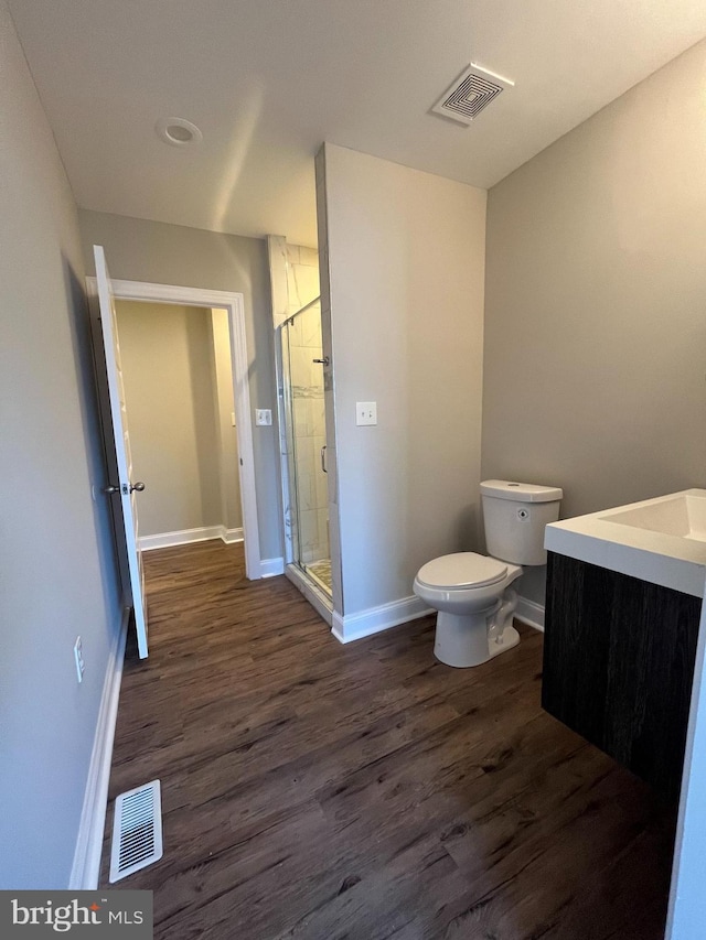 bathroom featuring vanity, toilet, wood-type flooring, and a shower with door