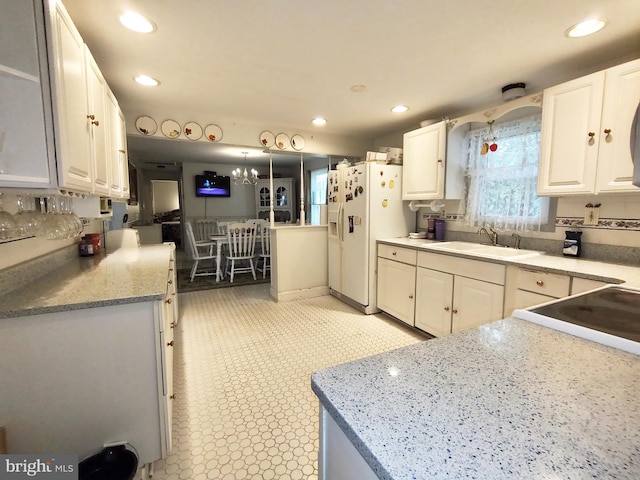 kitchen with white fridge with ice dispenser, white cabinets, pendant lighting, and sink