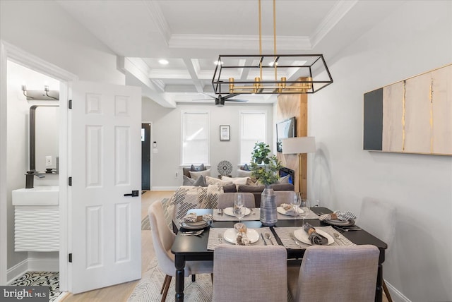 dining space with coffered ceiling, beamed ceiling, crown molding, light hardwood / wood-style flooring, and a chandelier