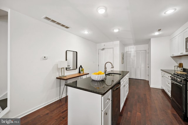 kitchen with dark wood-type flooring, black range with gas stovetop, white cabinets, a kitchen island with sink, and sink