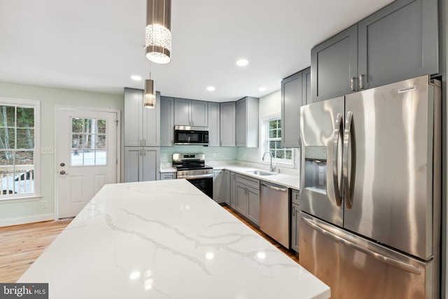 kitchen featuring sink, a healthy amount of sunlight, decorative light fixtures, and appliances with stainless steel finishes