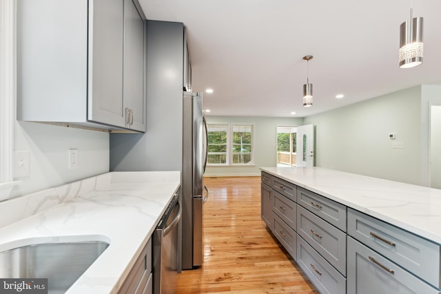 kitchen with decorative light fixtures, gray cabinets, appliances with stainless steel finishes, and light hardwood / wood-style flooring