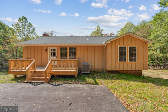 ranch-style house featuring a wooden deck, a front lawn, and central AC unit