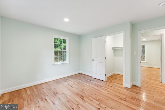 unfurnished bedroom featuring a walk in closet, light wood-type flooring, and a closet