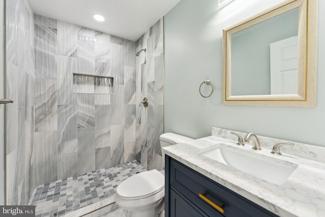 bathroom with tiled shower, vanity, and toilet