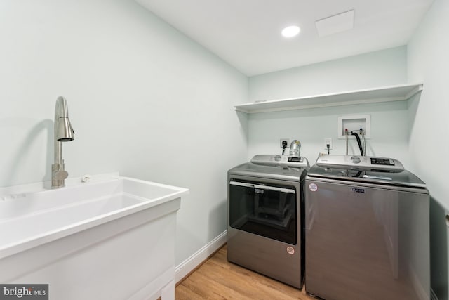 laundry room featuring washing machine and dryer, light hardwood / wood-style flooring, and sink