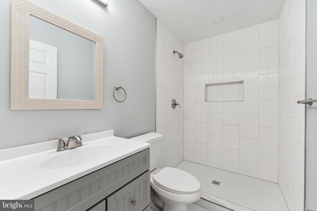 bathroom featuring tile patterned floors, vanity, toilet, and tiled shower