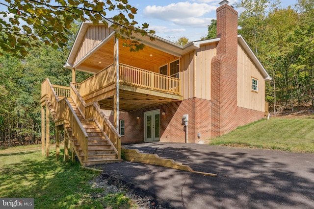 rear view of property featuring a yard, a wooden deck, and french doors