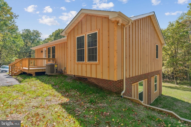 view of side of property with a wooden deck, a yard, and central AC