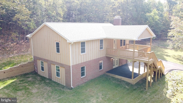 rear view of house featuring a lawn and a wooden deck