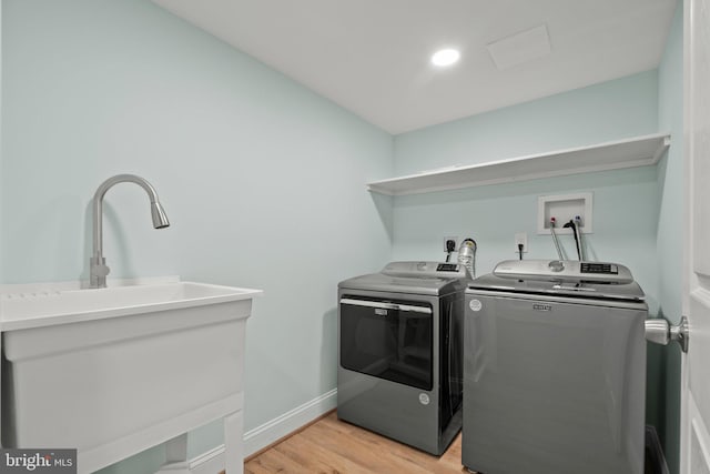 laundry area with light hardwood / wood-style floors and washing machine and clothes dryer