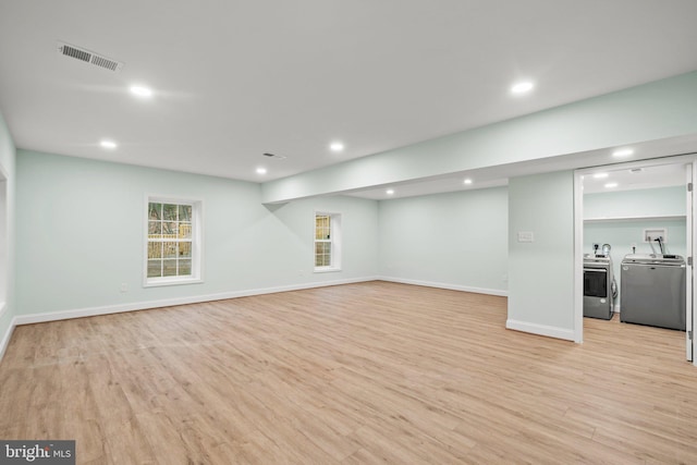 unfurnished living room featuring independent washer and dryer and light wood-type flooring