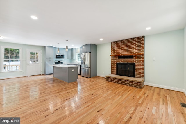 unfurnished living room with light wood-type flooring and a brick fireplace