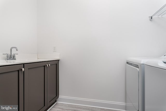 washroom with cabinets, light hardwood / wood-style flooring, and washing machine and dryer