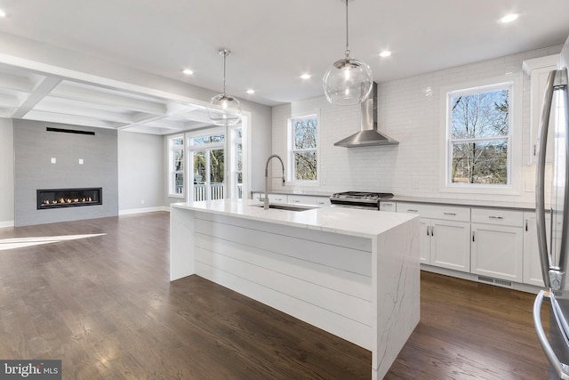 kitchen featuring hanging light fixtures, wall chimney exhaust hood, sink, and dark hardwood / wood-style flooring