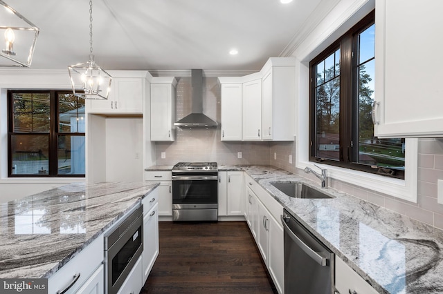 kitchen with wall chimney exhaust hood, stainless steel appliances, white cabinets, and pendant lighting