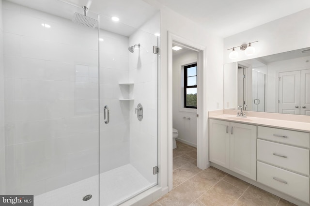 bathroom featuring vanity, toilet, an enclosed shower, and tile patterned floors