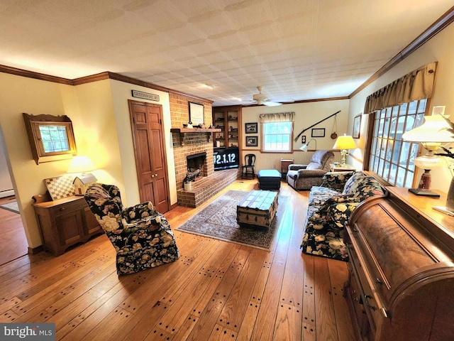 living room featuring a brick fireplace, ceiling fan, light hardwood / wood-style flooring, ornamental molding, and a baseboard heating unit