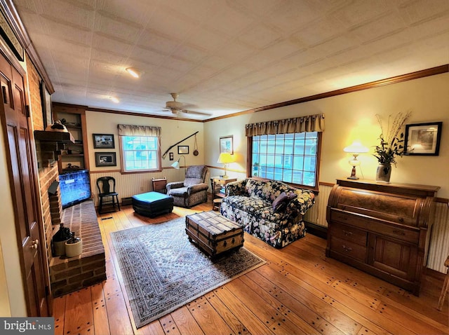 living room with crown molding, light hardwood / wood-style floors, a fireplace, and ceiling fan