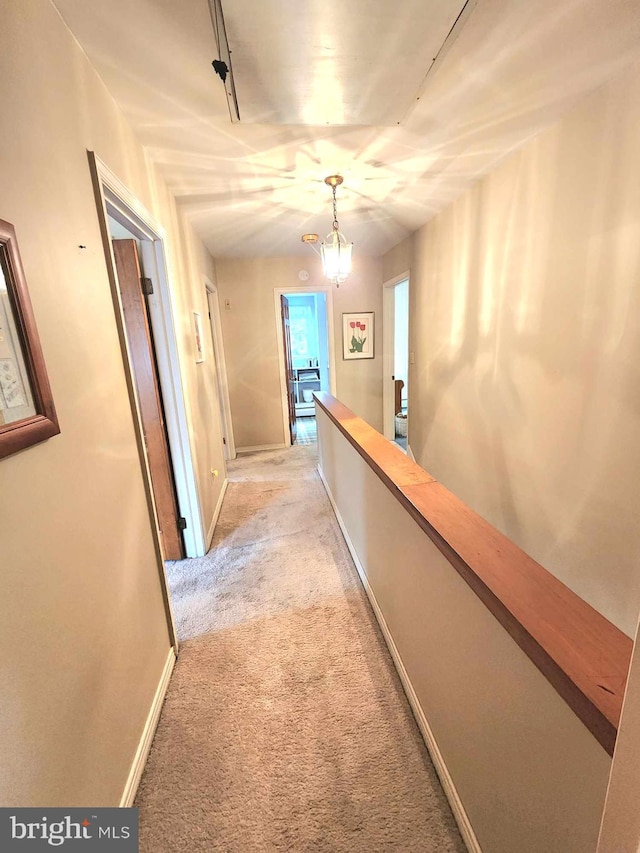 hallway featuring light carpet and a chandelier