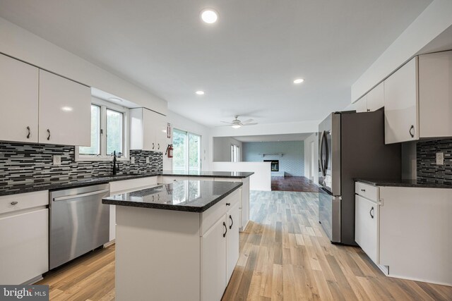 kitchen with a center island, white cabinetry, open floor plan, appliances with stainless steel finishes, and decorative backsplash