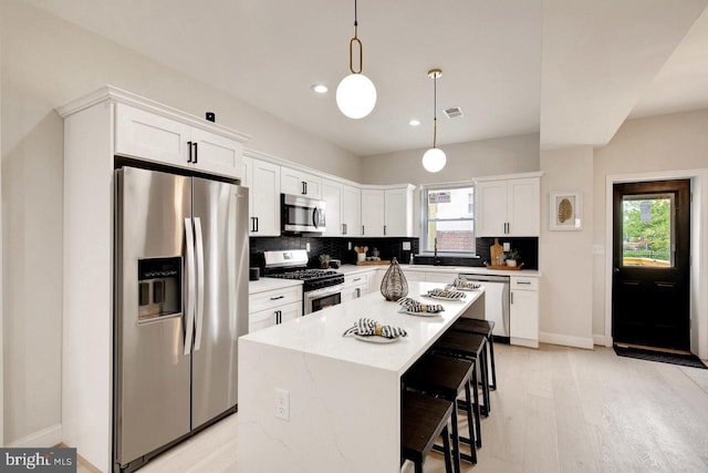 kitchen with pendant lighting, stainless steel appliances, a center island, and a healthy amount of sunlight