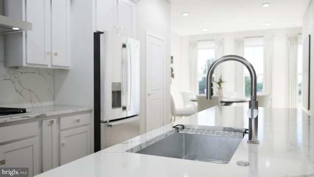 kitchen with white cabinets, sink, backsplash, ventilation hood, and white fridge with ice dispenser