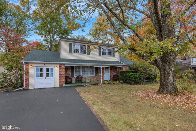 front of property with a porch, a front yard, and a garage