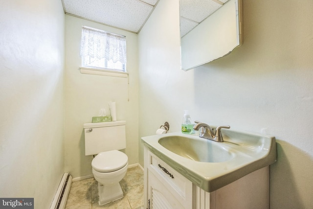 bathroom with toilet, tile patterned flooring, a baseboard heating unit, vanity, and a paneled ceiling