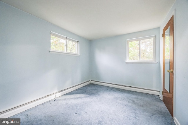 carpeted empty room featuring a baseboard heating unit