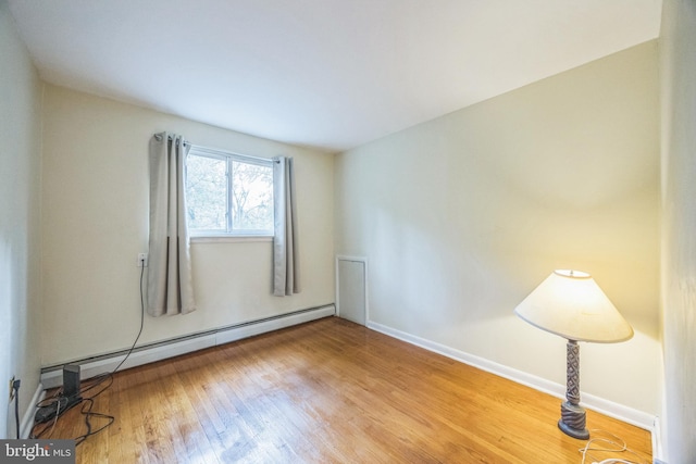 unfurnished room with hardwood / wood-style flooring and baseboard heating