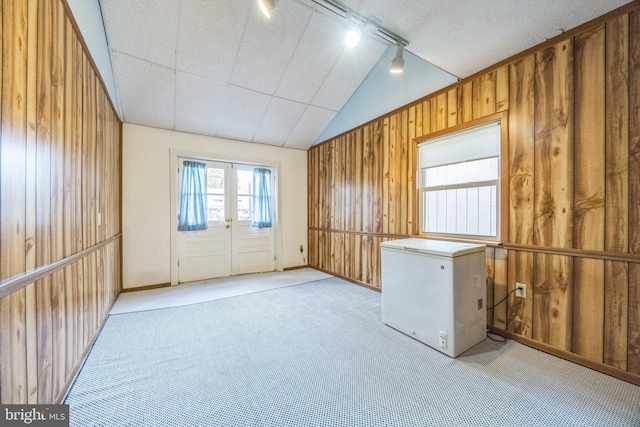 interior space featuring french doors, wood walls, track lighting, and vaulted ceiling