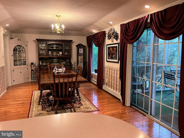 dining area featuring plenty of natural light, a notable chandelier, lofted ceiling, and light wood-type flooring