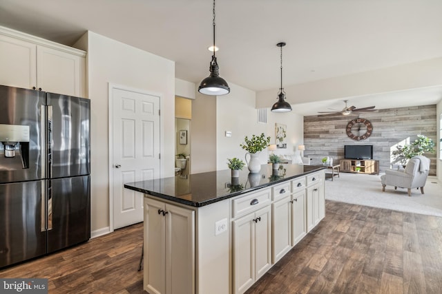 kitchen with white cabinetry, a kitchen island, ceiling fan, stainless steel refrigerator with ice dispenser, and wooden walls