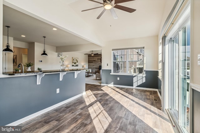 kitchen featuring a breakfast bar, kitchen peninsula, hardwood / wood-style floors, decorative light fixtures, and ceiling fan