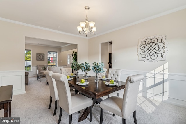 carpeted dining space with ornamental molding and an inviting chandelier