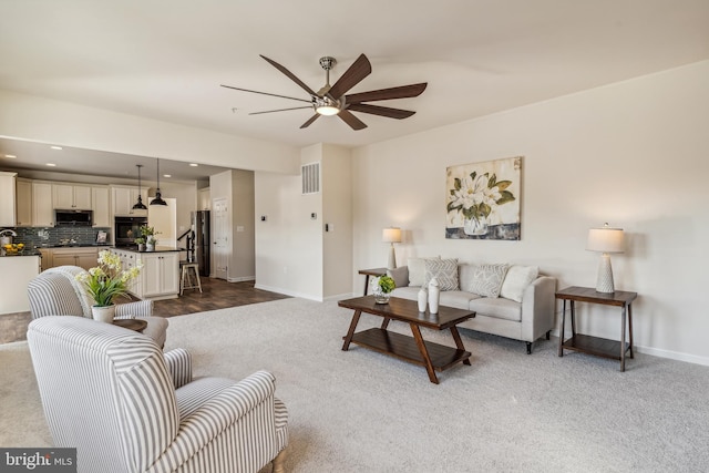 living room featuring ceiling fan and dark colored carpet