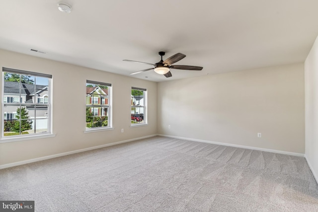 carpeted spare room with ceiling fan and plenty of natural light