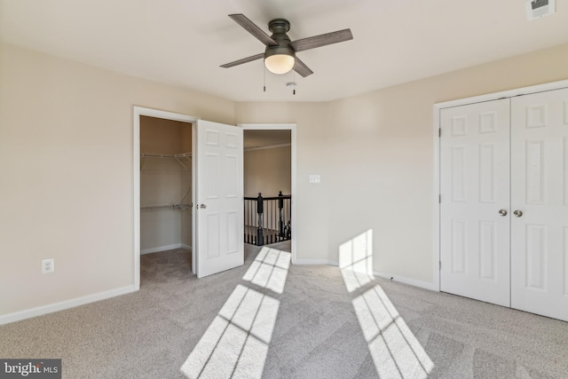 bedroom featuring ceiling fan, light carpet, and a walk in closet