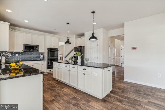 kitchen featuring dark wood-type flooring, decorative light fixtures, appliances with stainless steel finishes, and a kitchen island