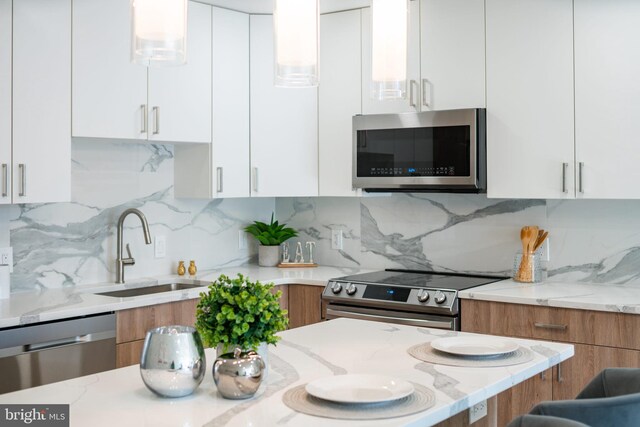 kitchen featuring appliances with stainless steel finishes, light stone counters, tasteful backsplash, white cabinets, and sink