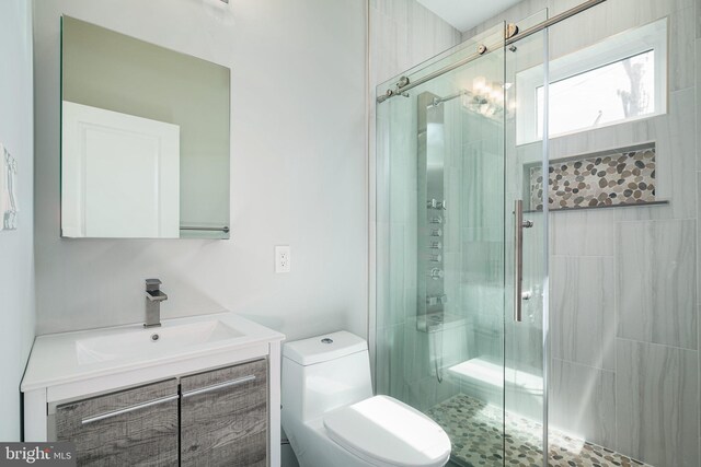 bathroom featuring vanity, toilet, and a shower with door