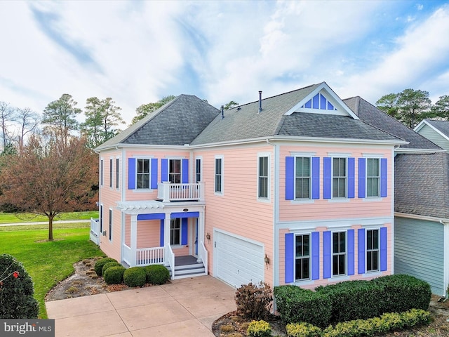 view of front of property featuring a balcony, a garage, and a front lawn