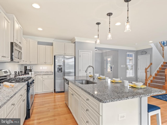 kitchen featuring stainless steel appliances, light hardwood / wood-style floors, a center island with sink, and sink