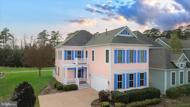 view of front of house with a yard, a garage, and a balcony