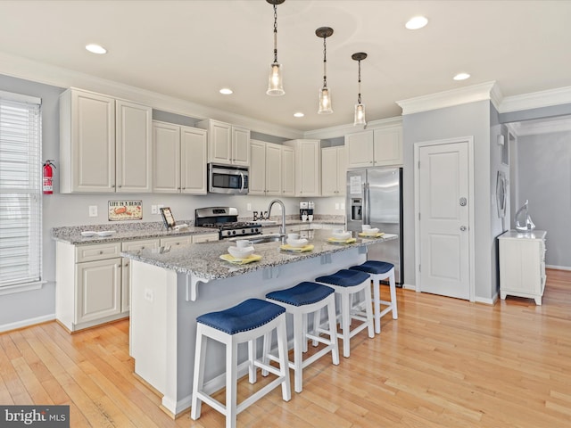 kitchen featuring hanging light fixtures, light stone counters, stainless steel appliances, light wood-type flooring, and ornamental molding