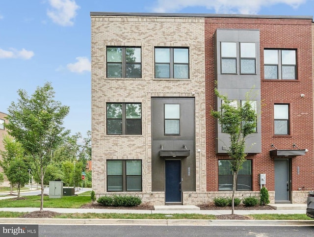 townhome / multi-family property with cooling unit and brick siding